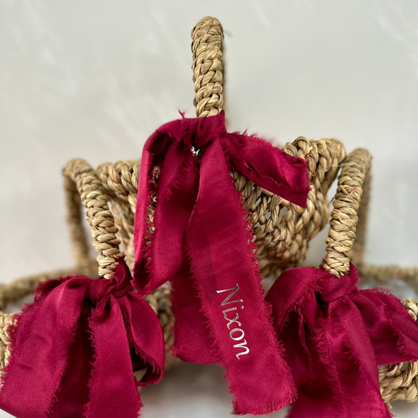 Red ribbons with personalized names tied around a woven basket